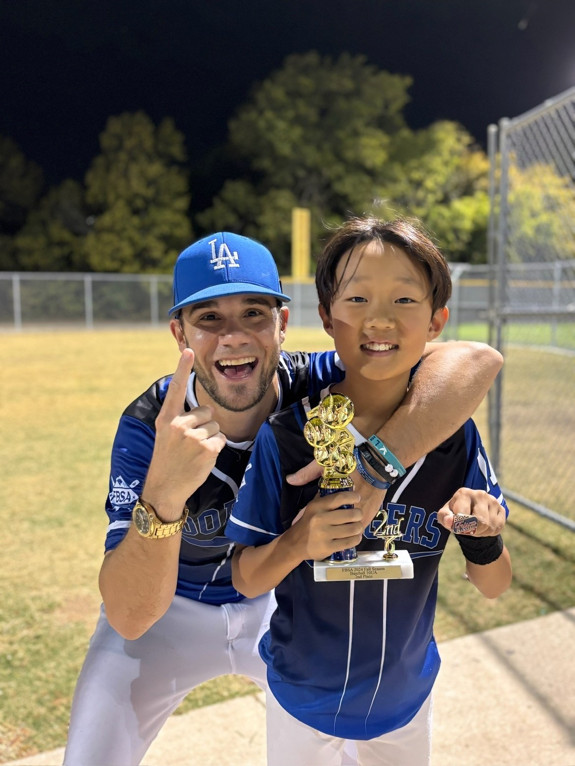 Matt Young with a young player holding a trophy and a championship ring